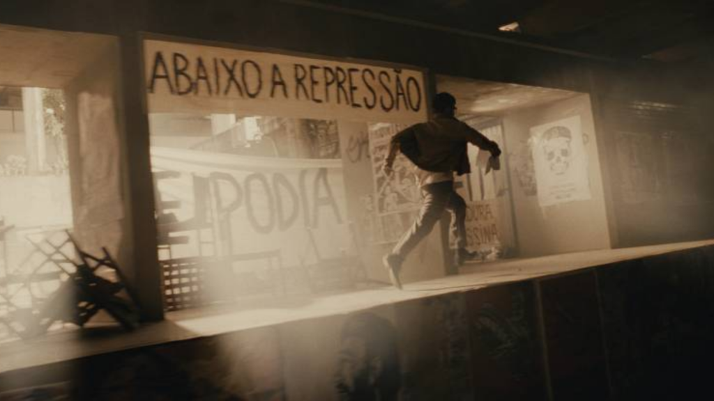 Cena de Honestino com Bruno Gagliasso correndo em meio a pichações contra a Ditadura