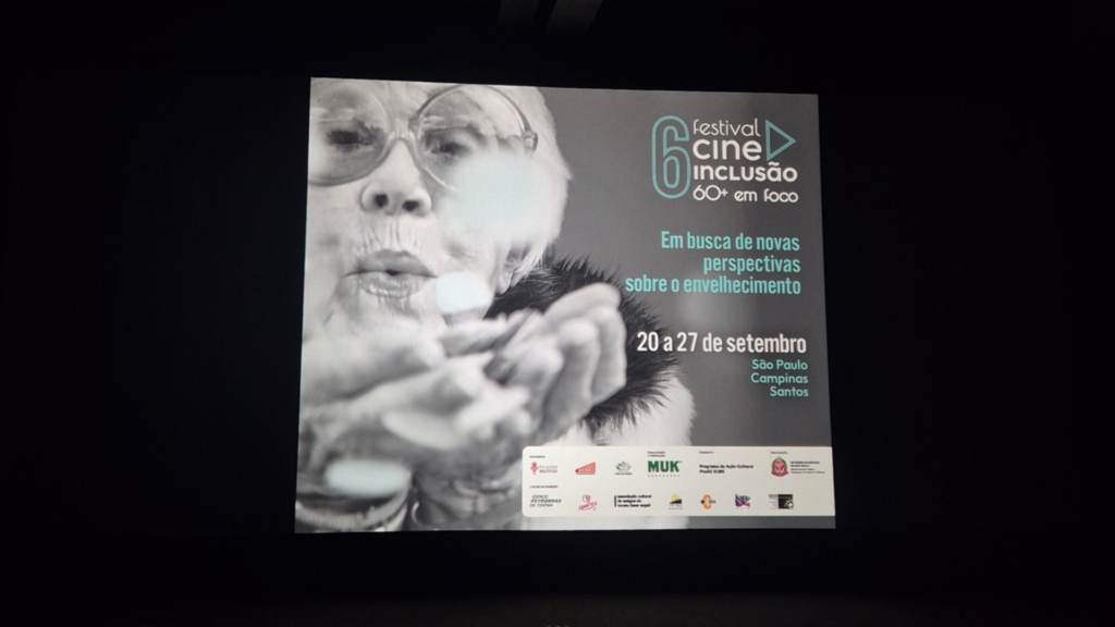 Foto mostrando a tela de cinema da sala com a arte de informações gerais da mostra Cine Inclusão.
